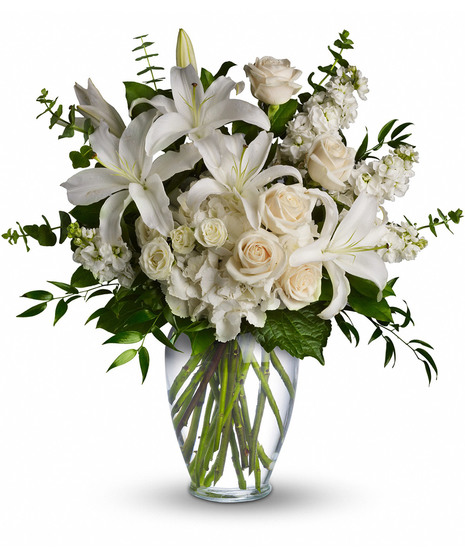 White and peach bouquet of lilies and roses with greenery in a clear glass vase