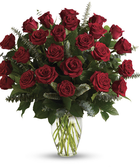 One dozen roses presented with greenery in a clear glass vase