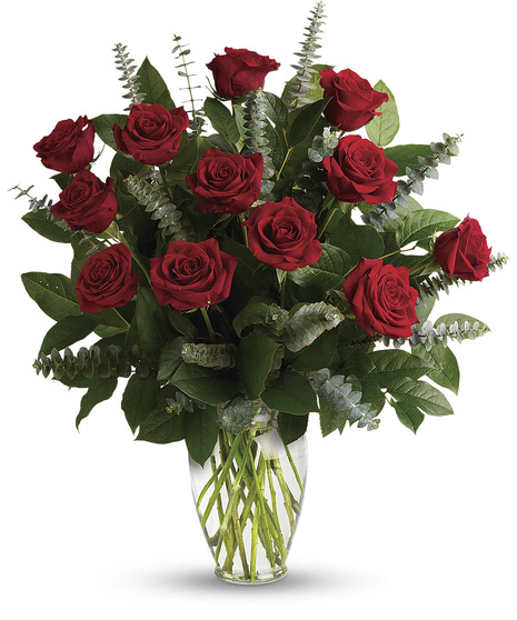 One dozen roses presented with greenery in a clear glass vase