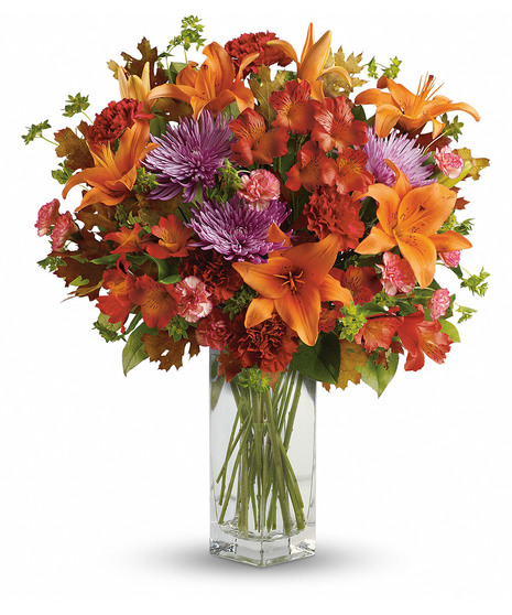 Orange lilies and red and lavender flowers in a tall rectangle vase
