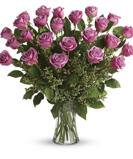 One dozen lavender roses and greenery in a clear glass vase