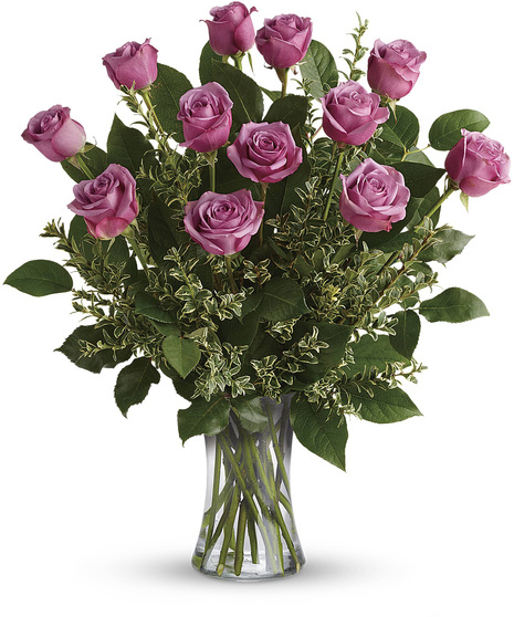 One dozen lavender roses and greenery in a clear glass vase