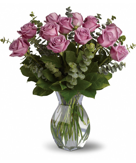 One dozen long stemmed lavender roses in a clear glass vase