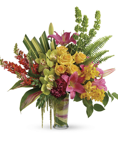 Bright bouquet of tropical flowers arranged in a leaf-lined glass vase