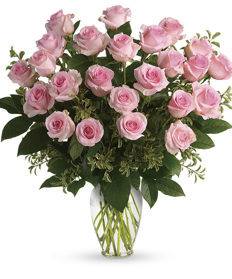 One dozen pink roses and greenery in a clear glass vase