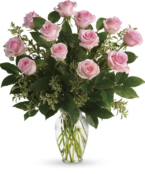One dozen pink roses and greenery in a clear glass vase