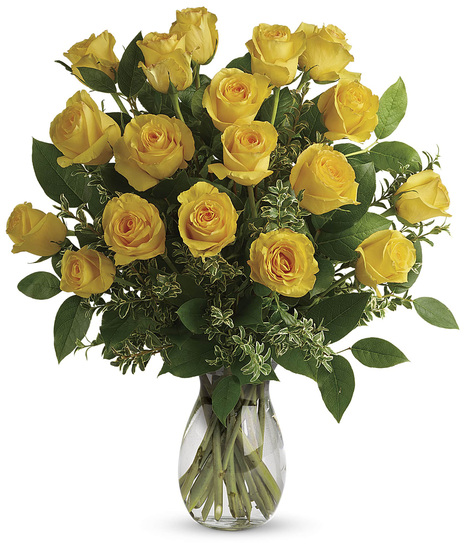 One dozen yellow roses and greenery in a clear glass vase