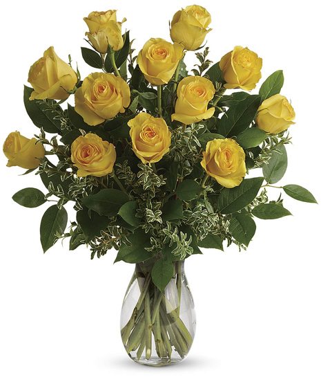 One dozen yellow roses and greenery in a clear glass vase